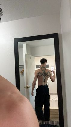 a shirtless man taking a selfie in the mirror