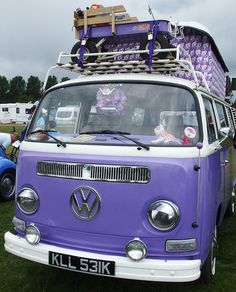 an old vw camper van with luggage on top parked in the grass at a car show