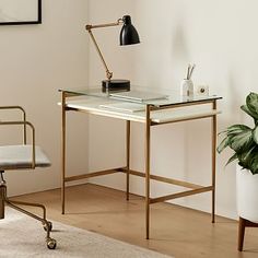 a desk with a chair, lamp and potted plant in the corner next to it