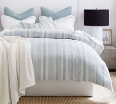 a bed with blue and white striped comforter in a bedroom next to a lamp