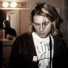 a man with long hair standing in front of a mirror