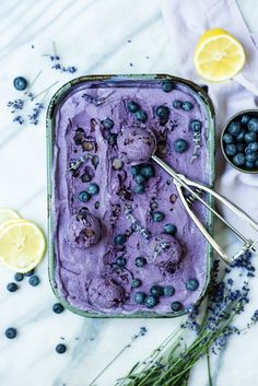 a pan filled with blueberries and ice cream next to lemon wedges on a table