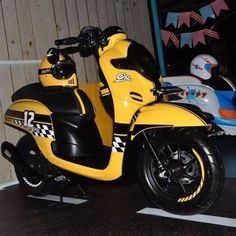 a yellow motor scooter parked in front of a building with decorations on the wall