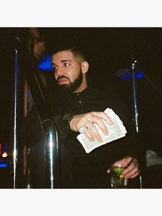 a man holding money in his hand while standing next to some microphones at night