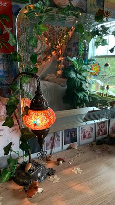 a lamp sitting on top of a wooden table next to a window filled with plants