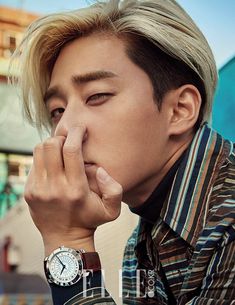 a young man with blonde hair and a watch on his wrist is posing for the camera