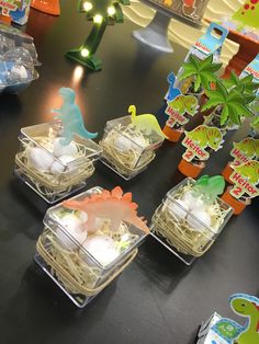 several plastic containers filled with food on top of a black table next to small trees