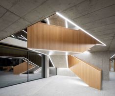 an empty room with wooden stairs and glass doors in the center is lit by recessed lights