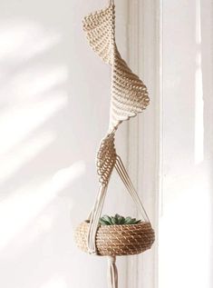 a hanging planter made out of wicker with plants in the bottom and on top