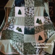 a green and white quilted blanket with trees on the front, sitting on top of a chair