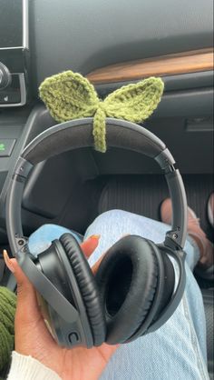 someone is holding their headphones up to the car stereo in front of them, with a green leaf on top