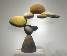 three rocks stacked on top of each other in front of a white wall and light