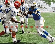 the football players are running on the field during the game, and one is holding the ball in his hand