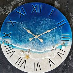 a blue clock with roman numerals on the face and beach in the background