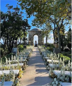 an outdoor ceremony set up with white flowers and greenery on the ground, surrounded by trees