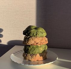 three cookies stacked on top of each other on a white plate in front of a wall