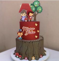 a red and white cake on top of a wooden tree stump with animals in it