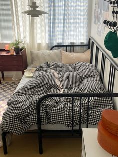 a bed with black and white checkered comforter in a bedroom next to a window