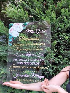 a woman is holding up a sign in front of some trees and bushes that say no quince