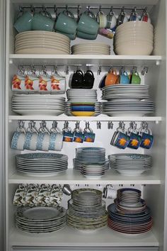 an open cabinet filled with dishes and plates