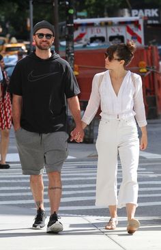 a man and woman walking down the street holding hands