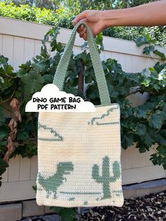 a crocheted bag hanging from a tree with the words dino game bag written on it