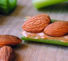 some almonds are sitting on top of a piece of green food with peanut butter