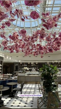 the ceiling is decorated with pink flowers and hanging from it's glass dome roof