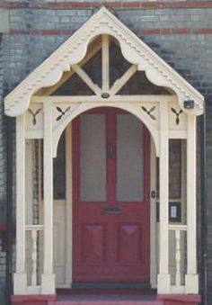 a red door is in front of a brick building with an arched doorway and white trim