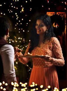 a woman in an orange dress is serving food to a man