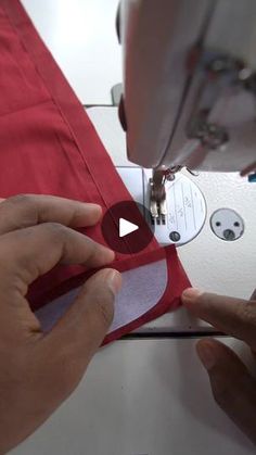 someone is using a sewing machine to sew on a red shirt with white buttons