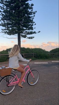 a woman riding a pink bike with a basket