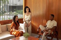 three people sitting on couches in a living room with wooden walls and flooring