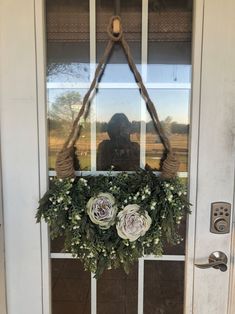 a wreath hanging on the front door with flowers and greenery attached to it's side