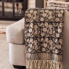 a couch with a blanket on it in front of a fireplace