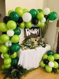 a table topped with green and white balloons next to a sign that says raw on it