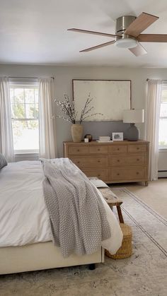 a bed room with a neatly made bed and a dresser next to the window in front of it