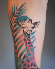 a colorful giraffe tattoo on the leg with palm leaves around it's neck