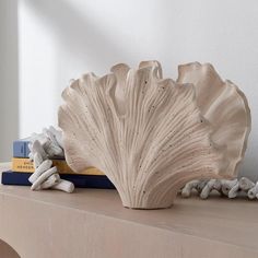 a white vase sitting on top of a wooden table next to a bookshelf