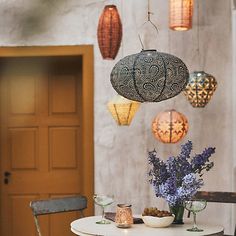 a table topped with plates and vases filled with purple flowers next to lanterns hanging from the ceiling