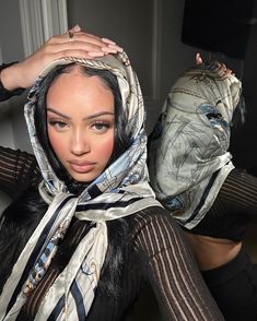 a woman in black and white is posing with her hands on her head while wearing a scarf