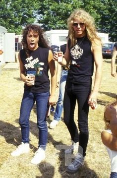 two women standing next to each other in front of a group of people holding drinks