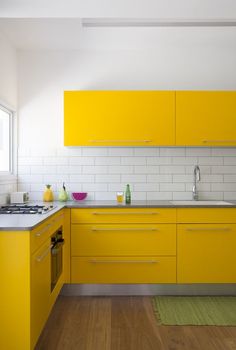 a kitchen with yellow cabinets and wooden floors