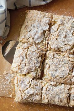 a wooden cutting board topped with lots of food next to a knife and bowl filled with powdered sugar