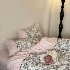 an unmade bed with black and white sheets, pink comforter, and pillows