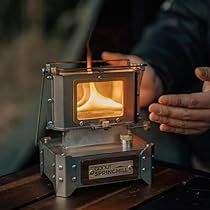 a person is holding out their hand to a small stove with a flame in it