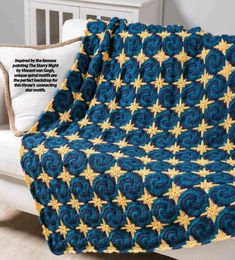 a crocheted blue and yellow blanket with gold stars on it sitting on a bed