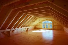 an empty attic with wooden floors and windows