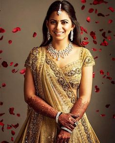 a woman wearing a gold and white outfit with red petals on the wall behind her