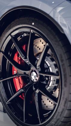 the front wheel of a sports car with red brake pads